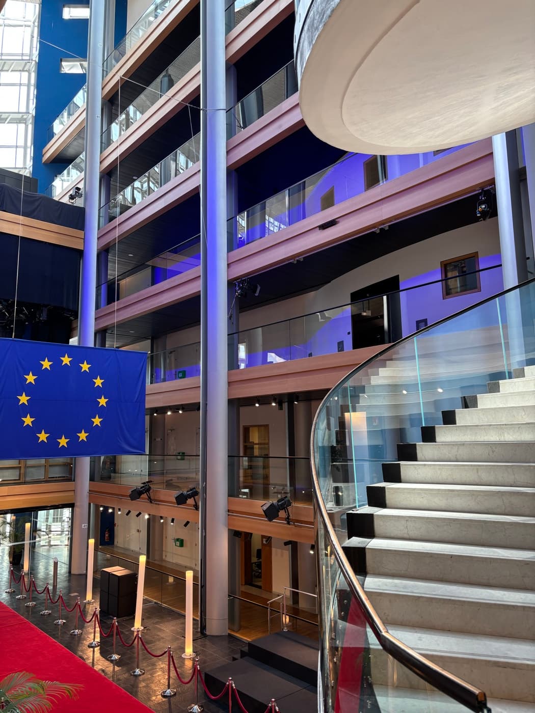 The European Parliament atrium with the EU flag hanging in the stairwell